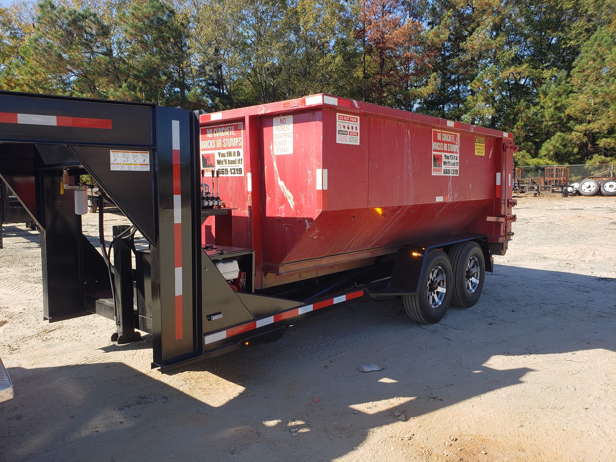 Red Knight Container Service roll-off dumpster loaded on a trailer